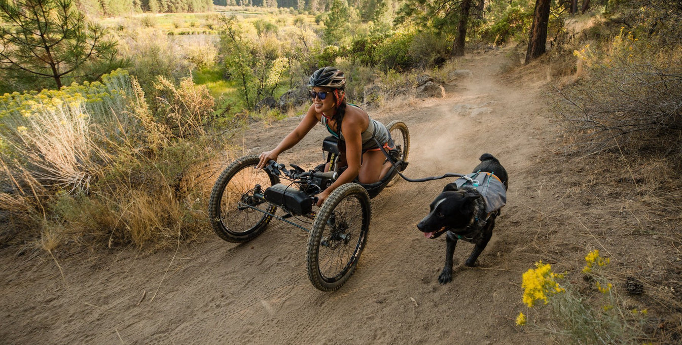 Anna on off road handcycle and Bernie on leash next to her bike down the River Trail in Bend.